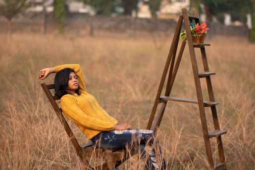 A portrait of a beautiful African female in a yellow sweater posing in a field