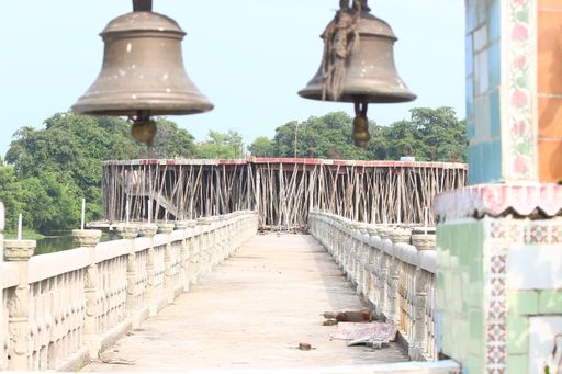 A closeup shot of two bells in the entrance of a bridge with trees in the background