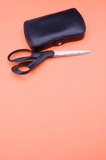 closed manicure set bag and scissors with copy space at the bottom on orange background
