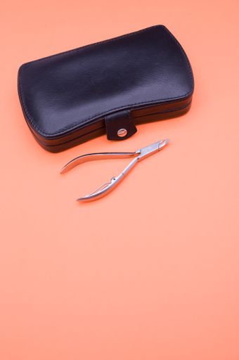 closed manicure set bag and nippers with copy space at the bottom on orange background