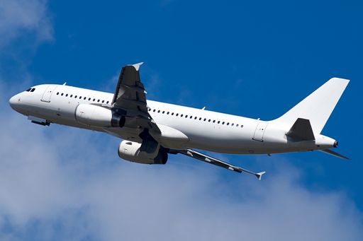 A big white airplane flying high against a blue cloudy sky on a sunny day