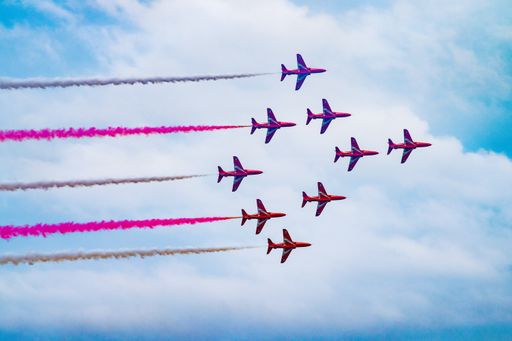 A scenic view of airplanes flying in the sky and leaving a pink trace behind