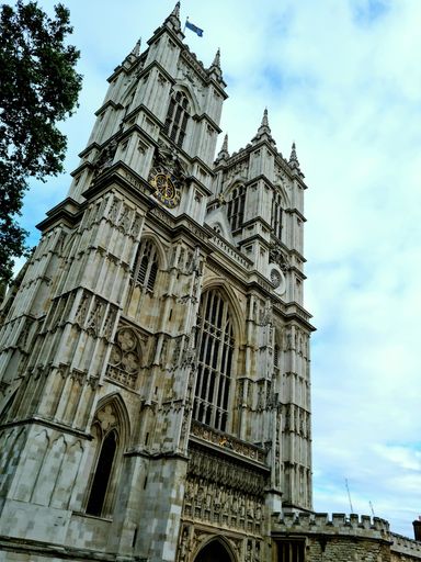 A vertical low angle shot of the Westminster Abbey with a blue sky and clouds above it