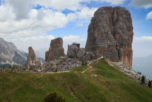 A beautiful view of rocky cliffs on a green hill in the mountains under a bright cloudy sky