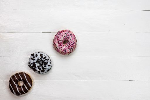 A top view of a donut with sprinkles on a wooden surface - copy space