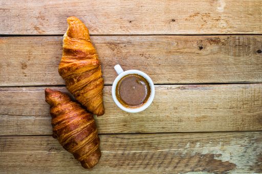 A top view of delicious fresh croissants and a cup of coffee on a table