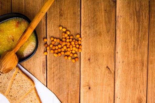 A top view of a bowl of soup with bread on a wooden table - copy space
