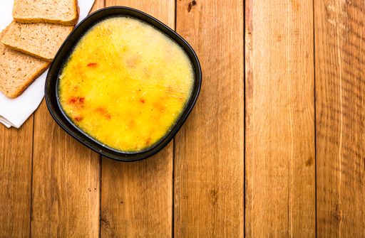 A top view of a bowl of soup with bread on a wooden table - copy space