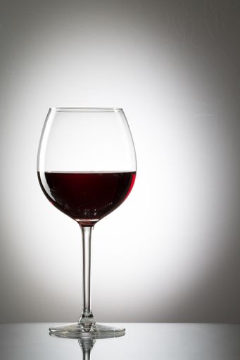 A glass of delicious red wine on a gray surface