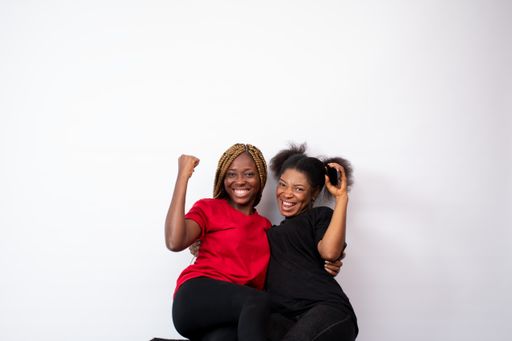 A pair of young African female friends happily posing isolated on a white background