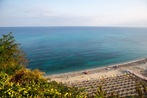An aerial shot of the beach with umbrellas and the seascape in Colabria region in Italy