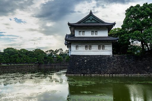 The Tokyo Imperial Palace surrounded by greenery and a lake under a cloudy sky in Japan