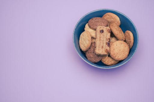 Vertical shot of biscuits in a bowl on a mauve background with text space
