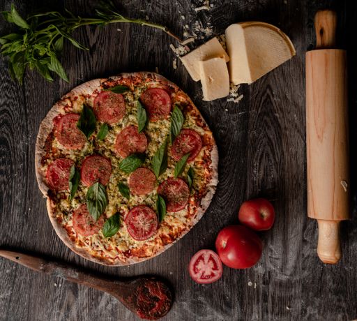 A top view of a gourmet pizza and ingredients on a wooden board