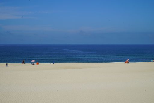 A breathtaking shot of a beach with some people sunbathing during the day