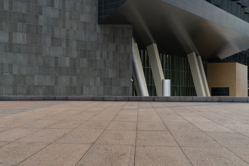 Modern architectural structure with geometric patterns and sleek lines, featuring a spacious foreground of tiled pavement.