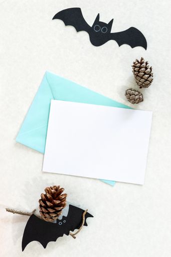 A top view of table with fun Halloween decorations and blank notecards with copyspace for invitations