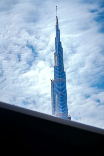 The Burj Khalifa tower in Dubai rises against a backdrop of a cloudy sky, showcasing its architectural marvel.