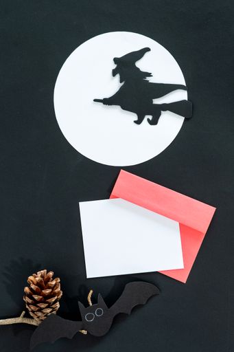 A top view of dark and spooky Halloween decorations and blank notecards with copyspace for invitations