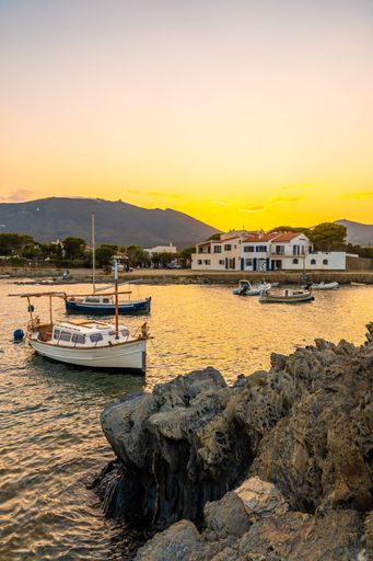 The sunset over the harbor captured from the beach of Platja De S'arenella in Cadaques, Spain