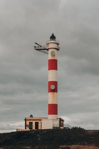 A vertical shot of a lighthouse with a cloudy sky in the background