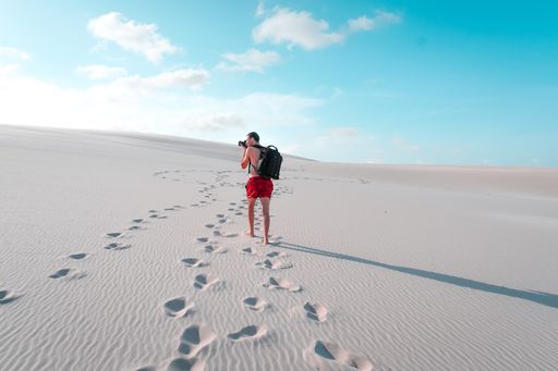 A scenic view of a Caucasian male taking a photo of the sandy dunes in Lencois National Park, North Brazil