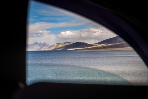 A scenic view from the car window of Pangong Lake and mountains in the background in Ladakh, India
