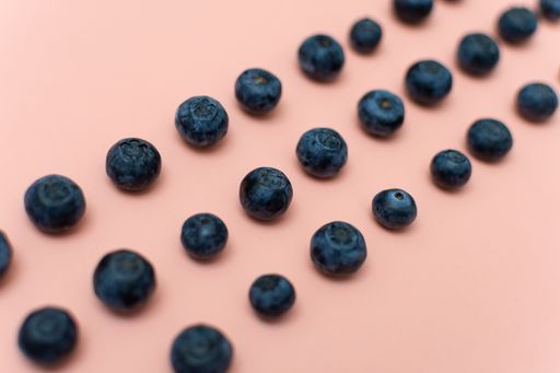 A closeup shot of rows of fresh blueberries isolated on a pink background