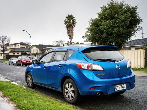 View of blue Mazda 3 car parked along road. Auckland, New Zealand - August 28, 2021