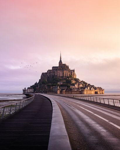 A road leading to the famous Mount Saint Michael on dramatic sunset in Normandy, France