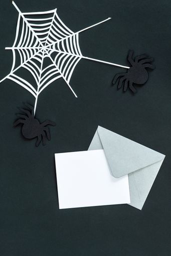 A top view of dark and spooky Halloween decorations and blank notecards with copyspace for invitations