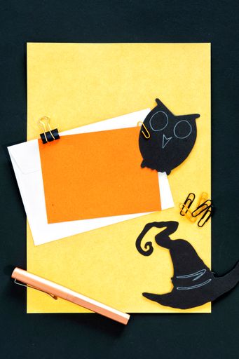 A top view of dark and spooky Halloween decorations and blank notecards with copyspace for invitations