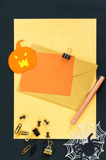 A top view of dark and spooky Halloween decorations and blank notecards with copyspace for invitations