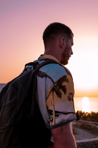 A close up shot from the back of a Caucasian (White) guy with a backpack and a blurry background in Romania