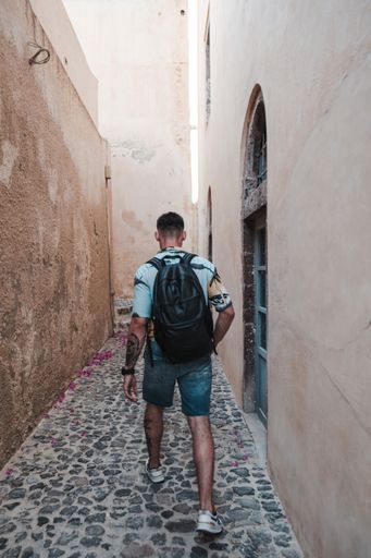 A closeup shot from the back of a Caucasian (White) guy with a backpack walking in street in Romania