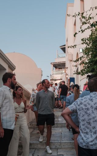 A vertical shot of people walking in the beautiful city of Santorini, Greece on a bright summer day