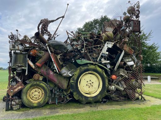 A bright summer day outdoors with a rusted old tractor full of junk