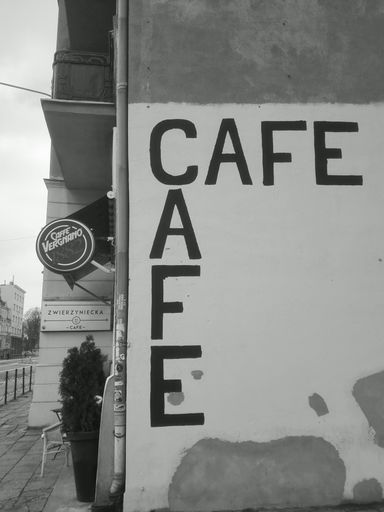 A grayscale shot of "cafe" text written on an old wall building in Poland