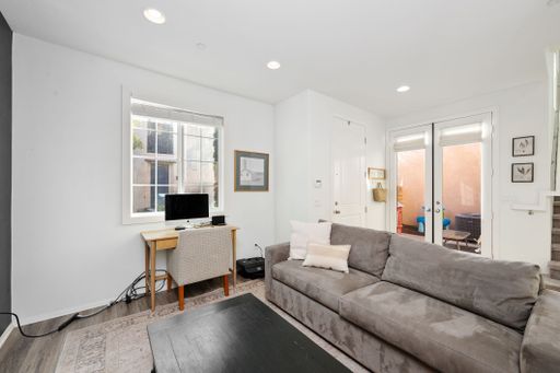 Modern living room with gray sofa, desk, and large window, featuring a cozy and bright atmosphere.
