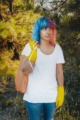 A vertical shot of a cheerful young female carrying a plastic garbage bag after cleaning the environment - plastic pollution concept
