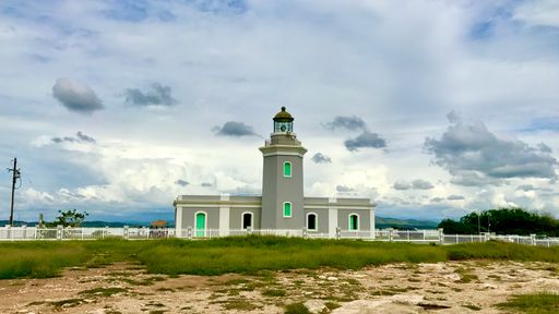 Los Morrillos Light surrounded by a field under a cloudy sky in Puerto Rico