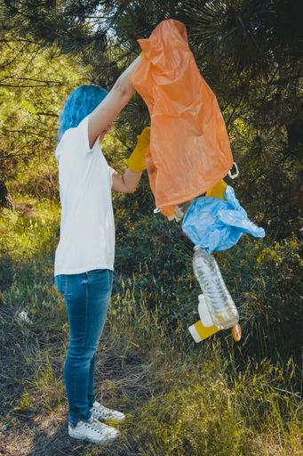 A young female collecting the trash and putting in a plastic garbage bag - environmental pollution concept