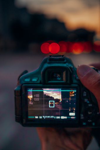 A vertical shot of a professional camera taking a picture outdoors