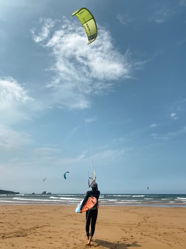 A vertical shot of a rear view of a person kitesurfing in Liencres, Cantabria, Spain
