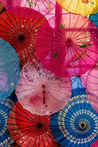 Colorful traditional Asian umbrellas with intricate floral patterns create a vibrant display.