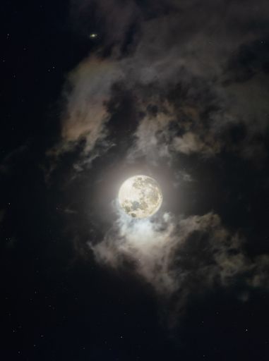 A vertical shot of the full moon and Saturn on a cloudy sky at night - perfect for wallpapers
