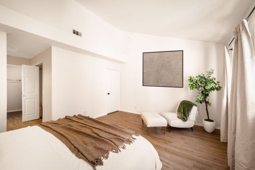 A minimalist bedroom with neutral tones, large windows, modern decor, soft lighting, and cozy furnishings