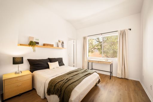 A minimalist bedroom with neutral tones, large windows, modern decor, soft lighting, and cozy furnishings
