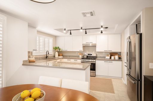 A living room and a kitchen with large windows, modern decor, soft lighting, and cozy furnishings