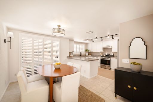 A living room and a kitchen with large windows, modern decor, soft lighting, and cozy furnishings